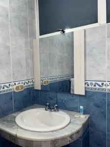 a bathroom with a sink and a mirror at Hotel Del Pacifico in Santo Domingo de los Colorados