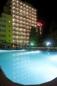 a large swimming pool in front of a hotel at night at Hotel Varshava in Golden Sands