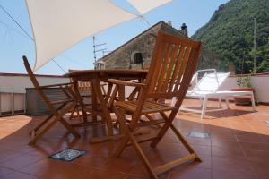 a wooden table and chairs on a patio with an umbrella at Donna Rosalia in Amalfi