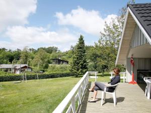 Eine Frau, die auf einem Stuhl auf der Veranda eines Hauses sitzt. in der Unterkunft 8 person holiday home in Sp ttrup in Lihme