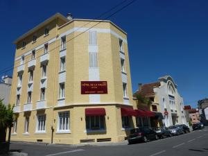 un edificio amarillo en la esquina de una calle en Cit'Hotel de La Vallée, en Lourdes