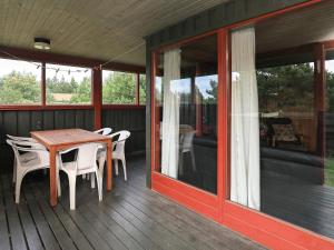 Torstedにある4 person holiday home in Thistedのポーチ(木製テーブル、椅子付)