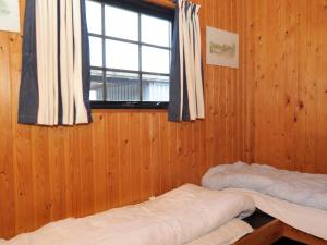 two beds in a wooden room with a window at Three-Bedroom Holiday home in Blåvand 2 in Blåvand