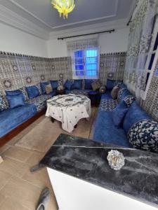 a living room with blue couches and a table at La petite villa avec piscine pieds dans l'eau in Sidi Rahal