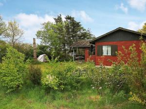 a red house in a field with a tent at 6 person holiday home in Vinderup in Vinderup