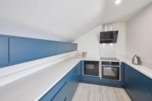 cocina con armarios azules y paredes blancas en Host & Stay - The Townhouse en Whitby