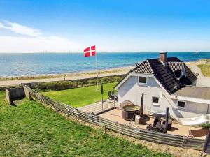 ein Haus mit einer Flagge vor dem Meer in der Unterkunft 8 person holiday home in Hurup Thy in Helligsø