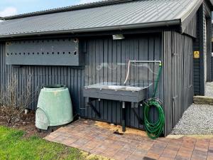 einen schwarzen Schuppen mit einem Waschbecken und einem grünen Schlauch in der Unterkunft 8 person holiday home in Hurup Thy in Helligsø