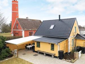 una casa amarilla con un faro en el fondo en Holiday home Læsø XLI, en Læsø