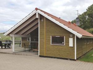 een klein huis met een dak en een patio bij 7 person holiday home in Broager in Broager