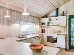 a kitchen with white cabinets and a wooden ceiling at Quaint Holiday Home in Nex with Beach nearby in Vester Sømarken