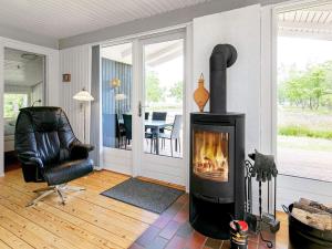 a living room with a fireplace and a chair at 8 person holiday home in H jslev in Sundstrup