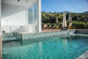 a swimming pool in a house with a glass wall at Pousada Vila do Lago - Vista Incrível, Café da Manhã e Passeio de Caiaque in Capitólio