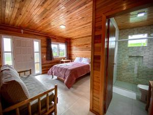 um quarto com uma cama e uma cabina de duche ao nível do chão em Pousada Flor do Campestre em Urubici