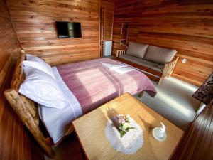 a bedroom with a bed and a table and a couch at Pousada Flor do Campestre in Urubici