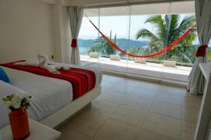 een slaapkamer met een bed en een groot raam bij Mexican Condo by the sea in Acapulco