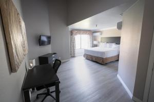ein Schlafzimmer mit einem Bett und einem Schreibtisch sowie ein Schlafzimmer mit einem Bett in der Unterkunft Alexis Park All Suite Resort in Las Vegas