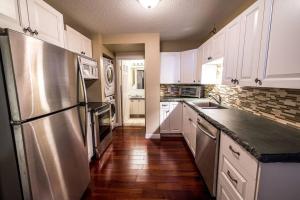 uma cozinha com armários brancos e um frigorífico de aço inoxidável em The River Blossom Suite - Downtown em Drumheller