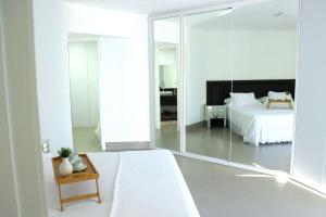 1 dormitorio con cama blanca y espejo grande en Haus Stay · pé na areia · Balneário Camboriú, en Balneário Camboriú