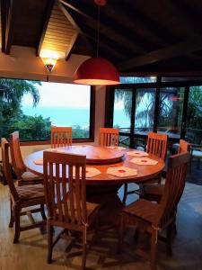 una sala da pranzo con tavolo, sedie e finestre di La Roca House a Praia do Rosa