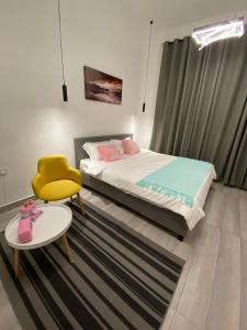 Platinum plus mirbat في صلالة: غرفة نوم بسرير وكرسي اصفر وطاولة