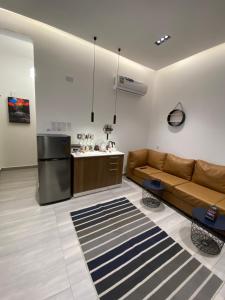 Platinum plus mirbat في صلالة: غرفة معيشة مع أريكة بنية ومطبخ