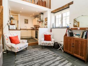 1 The Brass Bolt Shop في Perranwell: غرفة معيشة مع كرسيين ومطبخ