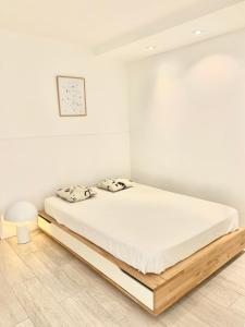 - une chambre blanche dotée d'un lit avec un cadre en bois dans l'établissement Loft Marina direct plage, à Villeneuve-Loubet