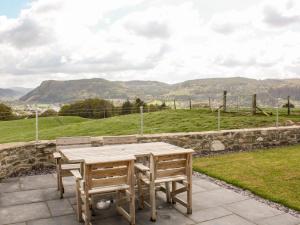 a wooden table and chairs on a patio with a view at Pen Y Bryn Cottage in Llanddoget