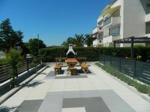 a table and benches on a sidewalk in front of a building at Apartman Linda in Medulin