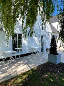 una casa bianca con due sedie e un albero di Egn Boutique Hotel a Stege