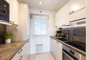 a kitchen with white cabinets and a sink at UnelmaHelmi in Ruka +12 photos