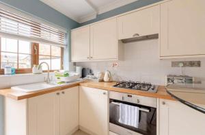 uma cozinha com armários brancos e um forno com placa de fogão em Rose Mews Central Broadstairs em Kent