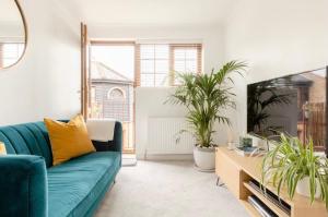 a living room with a green couch and two potted plants at Rose Mews Central Broadstairs in Kent