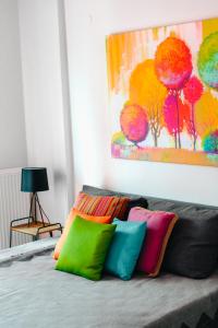 a bed with colorful pillows sitting under a painting at Sea Breeze Experience in Kavála