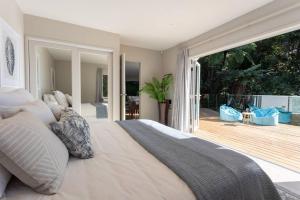 a bedroom with a large white bed and a balcony at Tree-top luxury in the Waitakere Ranges in Auckland