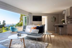 sala de estar con sofá, mesas y cocina en Tree-top luxury in the Waitakere Ranges, en Auckland