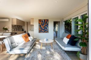 a living room with a couch and a table at Tree-top luxury in the Waitakere Ranges in Auckland