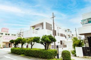 a white building with trees in front of it at 北谷日漁別荘 in Chatan
