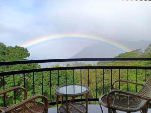 un arco iris sobre un balcón con sillas y mesa en Deshadan Mountain Resort -The highest resort in Munnar, en Munnar