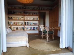 a bedroom with a bed and a chair and book shelves at Hillside Retreat – Africa Amini Life in Usa River