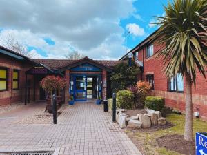 a building with a palm tree in front of it at Redwings Lodge Dunstable in Dunstable