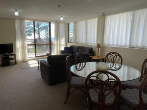 una sala de estar con una mesa y un sofá en Aries Holiday Apartments, en Gold Coast
