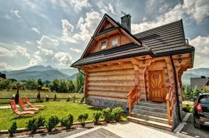 eine Blockhütte mit einer Veranda und einem Dach in der Unterkunft Karczogród in Kościelisko