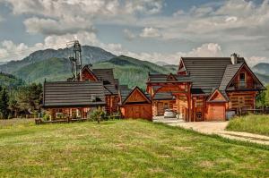 une grande maison en bois avec des montagnes en arrière-plan dans l'établissement Karczogród, à Kościelisko