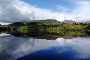 a reflection of a mountain in a body of water at Pitlochry North Wing Apartment - very central in Pitlochry