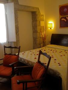 a bedroom with a bed and two chairs and a table at Hotel Villa Pimpina in Carloforte