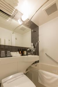 La salle de bains est pourvue de toilettes blanches et d'un lavabo. dans l'établissement Tosei Hotel Cocone Asakusa, à Tokyo