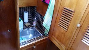 a small kitchen with a sink and a mirror at Boat Stoer kamperen op het water - niet om mee te varen - lees hostprofiel-read host profile in Jutrijp