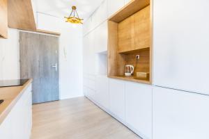 a kitchen with white countertops and wooden cabinets at Apartament AHOJ!!- Giżycko/ Wilkasy in Wilkasy